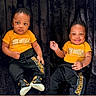 baby, child, infant, toddler, smile, dimples, clothing, yellow_shirt, black_pants, sneakers, matching_outfits, portrait, indoor, seated, cute, happy, serious, two_children, black_background, fashion