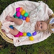 Eden is registered to the contest to win money with this photo: baby, basket, bonnet, clothing, easteregg, egg, face, food, grass, hat, head, homedecor, lawn, linen, person, photography, plant, portrait, purple, sweets