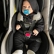 Inacio participe au concours pour gagner de l'argent avec cette photo : baby, car_seat, pacifier, hoodie, black_clothing, white_socks, infant, child, seat_belt, safety, cute, indoor, person, small_hands, footwear, clothing, infant_care, baby_accessory, portrait, car_interior