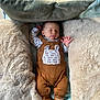 baby, sleeping, brown_overalls, boots, pillows, blankets, cozy, infant, soft_texture, resting, cute, child, indoors, comfortable, peaceful, clothing, portrait, warm, nursery, relaxing