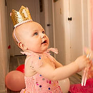 Nova Rae joined the competition — help win amazing prizes! baby, child, crown, birthday, party, pink_dress, balloons, indoor, toy, celebration, number_one, happy, smiling, person, floor, hand, decorations, sequins, toddler, festive