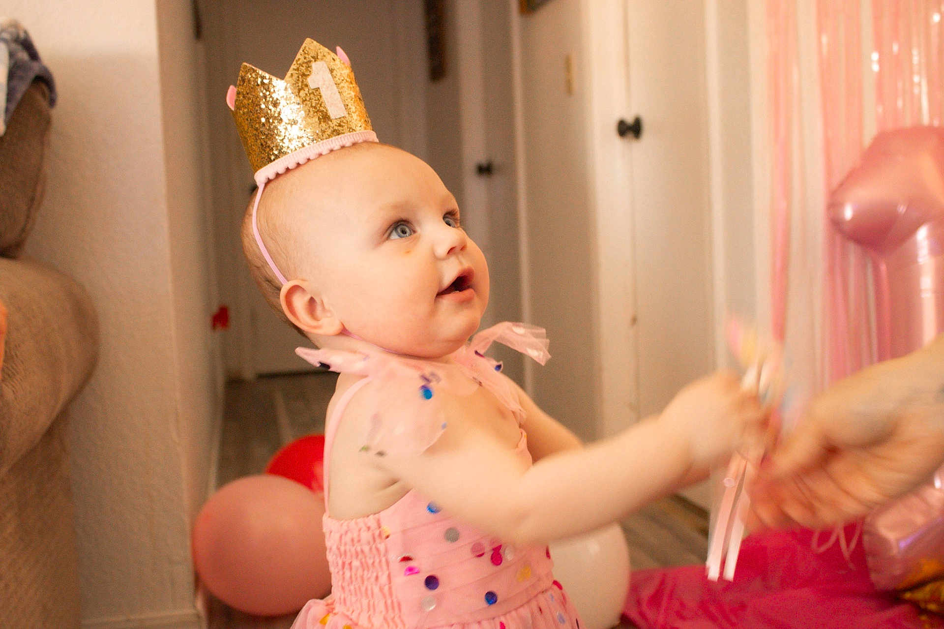 Nova Rae joined the competition — help win amazing prizes! baby, child, crown, birthday, party, pink_dress, balloons, indoor, toy, celebration, number_one, happy, smiling, person, floor, hand, decorations, sequins, toddler, festive