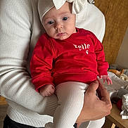 Anna a rejoint le concours — aidez-le/la à gagner de superbes lots ! adult, baby, bow, child, clothing, cozy, curious, cute, furniture, hand, headband, holding, indoor, infant, leggings, person, portrait, red_sweater, table, white_sweater