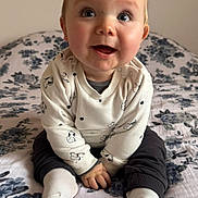 Louka a rejoint le concours — aidez-le/la à gagner de superbes lots ! baby, child, infant, smiling, sitting, bed, blanket, clothing, socks, cute, happy, portrait, indoor, face, hands, blue, white, pattern, cozy, young