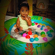 Julie Kay is registered to the contest to win money with this photo: toddler, child, inflatable_pool, foam, plastic_balls, colorful, indoor, curious, play, water, green, yellow, red, blue, pink, orange, person, baby, sitting, cute