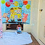 toddler, child, sunglasses, red_sunglasses, blanket, banner, cocomelon, cartoon, balloons, bubbles, floor, tiles, door, wall, casual_clothing, smiling, party, celebration, outdoor, playful
