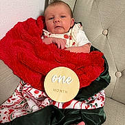 Grace is registered to the contest to win money with this photo: baby, infant, blanket, red_blanket, green_satin, wooden_sign, one_month, milestone, chair, tufted_chair, foot, bare_foot, festive, holiday, patterned_blanket, face, person, cute, portrait, indoors