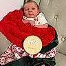 baby, infant, blanket, red_blanket, green_satin, wooden_sign, one_month, milestone, chair, tufted_chair, foot, bare_foot, festive, holiday, patterned_blanket, face, person, cute, portrait, indoors