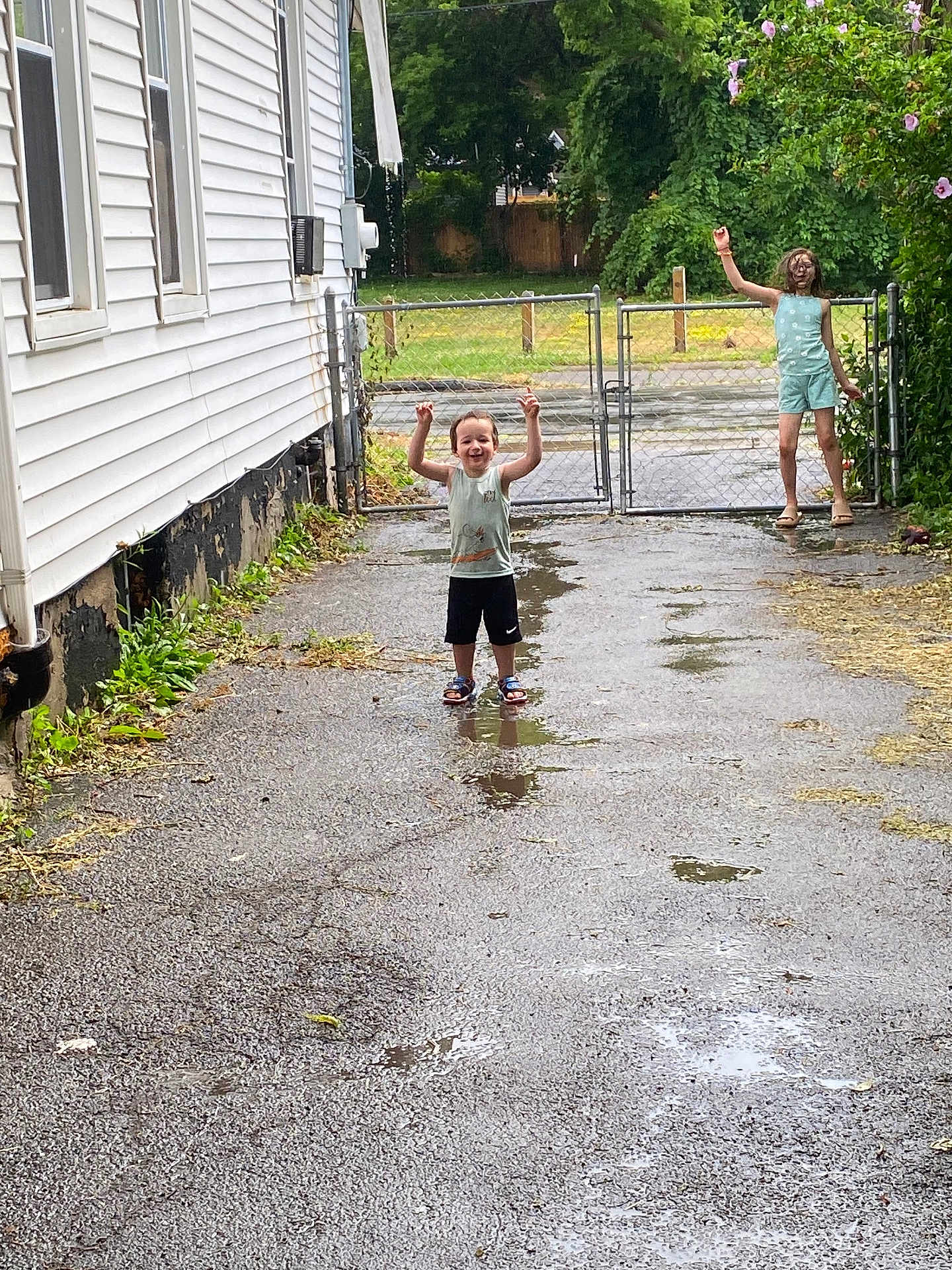 Itachi joined the competition — help win amazing prizes! child, children, playful, outdoor, driveway, puddle, wet_ground, gate, house, greenery, flowers, summer_clothing, smiling, happy, trees, sidewalk, nature, fence, casual, daytime