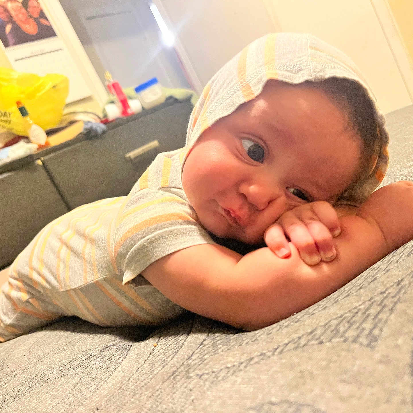 Raeshayn joined the competition — help win amazing prizes! baby, infant, child, hooded_onesie, striped_clothing, bed, bedroom, toy, resting, curious_expression, pouty, arms, face, skin, sleepwear, cozy, furniture, background, indoor, person