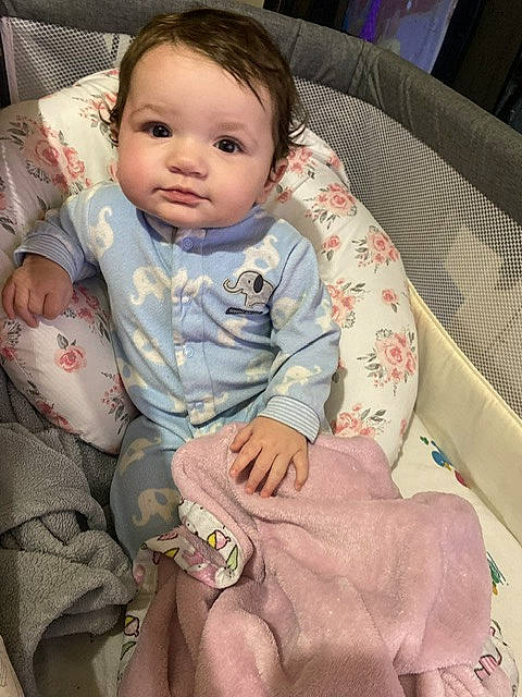 Scarlett is registered to the contest to win money with this photo: arm, baby, baby_products, baby_toddler_clothing, cheek, child, chin, comfort, couch, finger, head, lap, linens, mouth, nose, person, sitting, skin, sleeve, textile