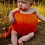 baby, bodypart, clothing, face, finger, food, grass, hand, head, outdoors, person, photography, plant, portrait, produce, pumpkin, sitting, soil, squash, vegetable