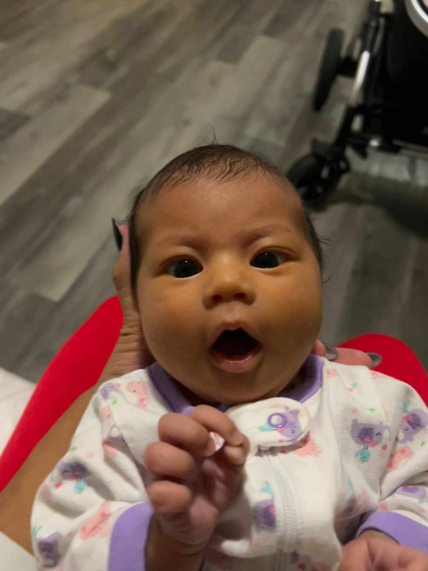 Aymee joined the competition — help win amazing prizes! baby, infant, hand, onesie, purple_trim, animal_prints, curious_expression, wide_eyes, open_mouth, person, indoor, floor, stroller, nails, holding, clothing, portrait, close_up, child, cute