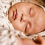 baby, sleeping, close_up, headband, floral_pattern, infant, peaceful, soft_lighting, skin, face, mouth, nose, eyelids, clothing, fabric, texture, cute, rest, child, portrait