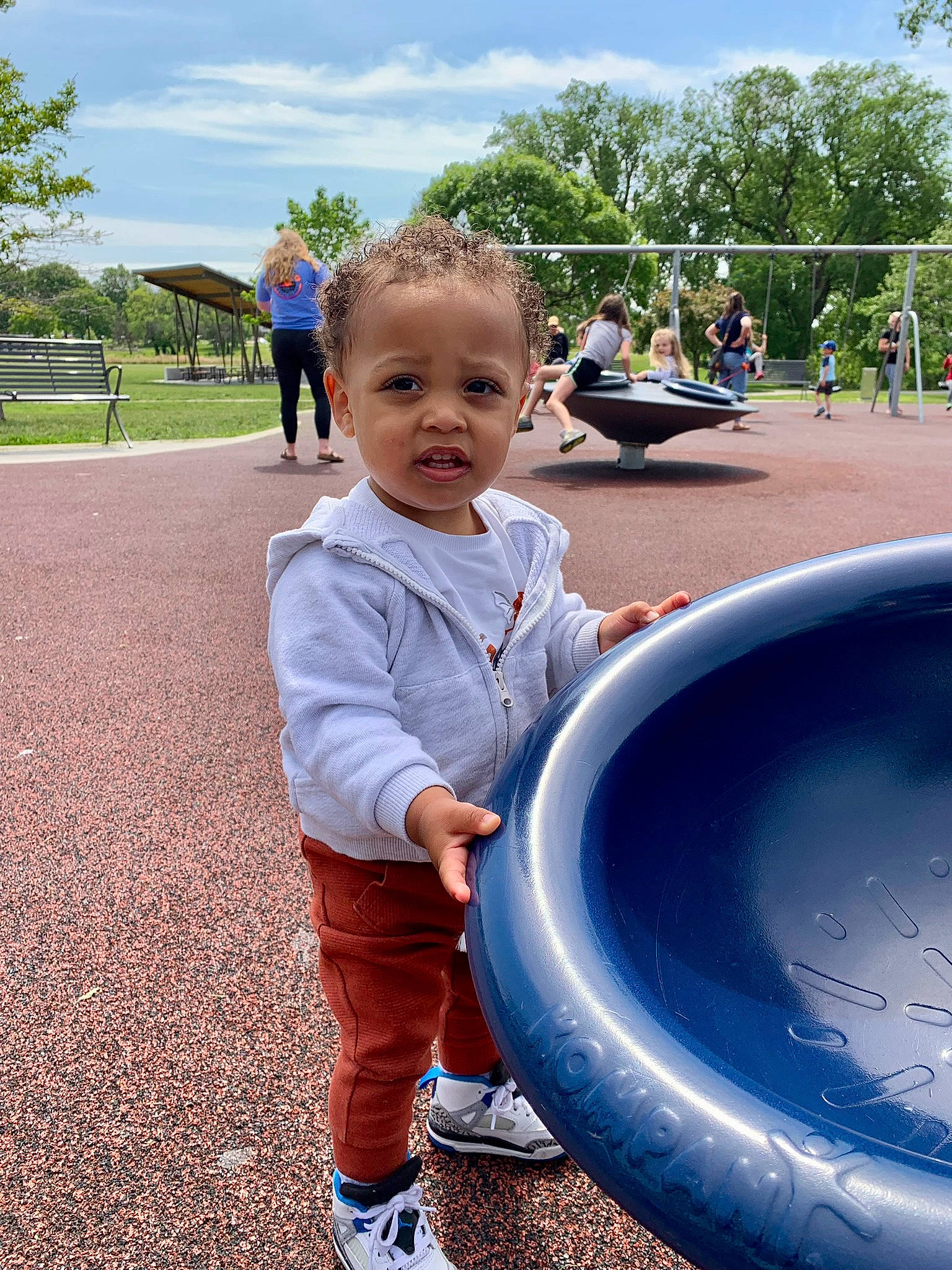 Lance is registered to the contest to win money with this photo: automotive_tire, blue, child, city, clothing, cloud, fun, grass, green, leisure, people, person, plant, playground, public_space, recreation, sky, sneakers, tire, toddler