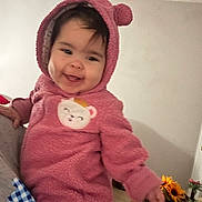 Ashley is registered to the contest to win money with this photo: baby, child, hoodie, pink_clothing, smiling, face, person, indoors, flower, sunflower, table, bottle, plant, hand, cute, cozy, warm_clothing, home, infant, portrait