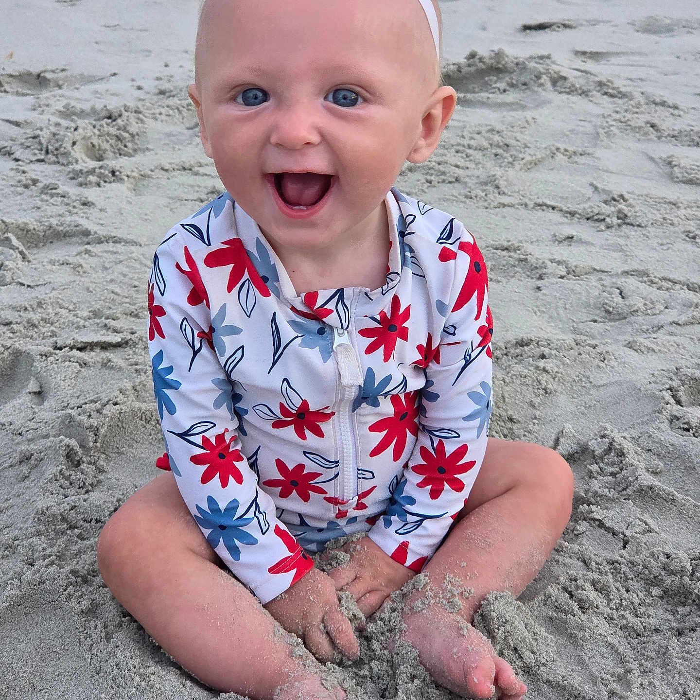 Rose joined the competition — help win amazing prizes! baby, child, beach, sand, smile, happy, headband, bow, swimsuit, floral_pattern, sitting, barefoot, outdoor, sunlight, cute, playful, portrait, person, infant, summer