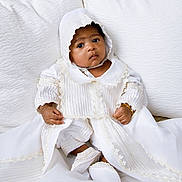 Lior joined the competition — help win amazing prizes! baby, infant, child, white_clothing, bonnet, christening_gown, cushion, fabric, portrait, sitting, cute, indoors, soft_lighting, closeup, face, hands, footwear, bracelet, serene, curious