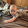 Aiden joined the competition — help win amazing prizes! baby, infant, bed, toy, bottle, blanket, clothing, face, person, wooden_wall, patterned_bag, brown_bedspread, reaching_hand, indoor, cute, child, plush_toy, sitting, curious, soft_toy