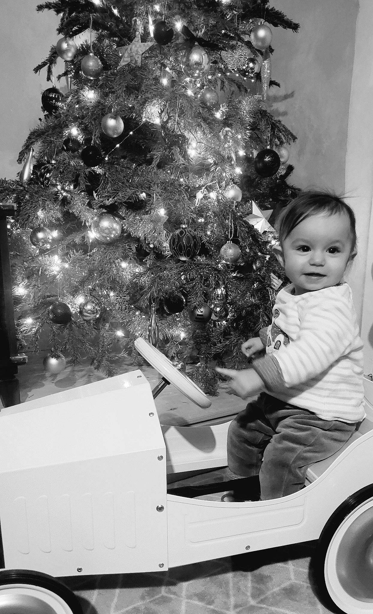 Inès participe au concours pour gagner de l'argent avec cette photo : black, christmas_decoration, christmas_ornament, christmas_tree, event, evergreen, hair, happy, head, holiday_ornament, monochrome_photography, ornament, person, riding_toy, standing, tints_and_shades, tire, tree, vehicle, wheel