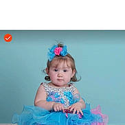 Anora is registered to the contest to win money with this photo: toddler, child, dress, blue, pink, hair_accessory, frills, sitting, portrait, cute, baby, innocent, curious, studio, background, chubby_cheeks, person, fashion, young_child, smile