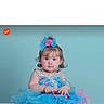 toddler, child, dress, blue, pink, hair_accessory, frills, sitting, portrait, cute, baby, innocent, curious, studio, background, chubby_cheeks, person, fashion, young_child, smile