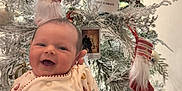Ruairi is registered to the contest to win money with this photo: baby, smiling, christmas_tree, ornaments, pinecones, stockings, festive_outfit, holiday, celebration, infant, happy, decorations, white_tree, cute, seasonal, christmas, joyful, holiday_lights, portrait, indoors