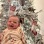 baby, smiling, christmas_tree, ornaments, pinecones, stockings, festive_outfit, holiday, celebration, infant, happy, decorations, white_tree, cute, seasonal, christmas, joyful, holiday_lights, portrait, indoors