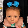 baby, blue_bow, blue_eyes, car_seat, child, child_seat, closeup, clothing, curly_hair, cute, face, hand, indoor, infant, looking, pink_bow, portrait, safety, seatbelt, tie_dye_shirt