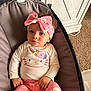 baby, baby_seat, bow, carpet, child, comfortable, cozy, curly_hair, cute, expression, headband, hello_kitty, indoor, infant, onesie, pants, pink_clothing, plush_toy, portrait, soft_lighting