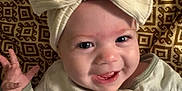Noelle is registered to the contest to win money with this photo: baby, bow, cheerful, child, closeup, cute, eyes, face, hand, happy, headband, indoors, infant, lying_down, mouth, onesie, patterned_blanket, skin, smiling, teeth