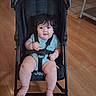 Maria joined the competition — help win amazing prizes! baby, child, stroller, sitting, indoors, portrait, face, smiling, wide_eyed, dark_hair, blue_eyes, onesie, harness, harness_buckle, bare_feet, wooden_floor, kitchen, furniture, wheel, photography