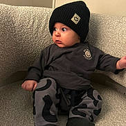 Cohen joined the competition — help win amazing prizes! baby, child, hat, black_hat, smiley_face, sitting, couch, gray_couch, pants, patterned_pants, long_sleeve_shirt, indoors, cute, portrait, person, knit_hat, expression, looking_away, cozy, casual_wear
