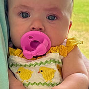 Poppy is registered to the contest to win money with this photo: baby, child, closeup, cute, embroidered_chicks, eyes, face, field, flower, hand, headband, holding, infant, outdoor, pacifier, person, portrait, skin, soft_light, yellow_clothing