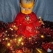Gabie participe au concours pour gagner de l'argent avec cette photo : baby, child, christmas_lights, tinsel, red_clothing, socks, holiday, festive, indoors, glowing, string_lights, cute, toddler, celebration, smiling, decoration, warm_light, person, sitting, background