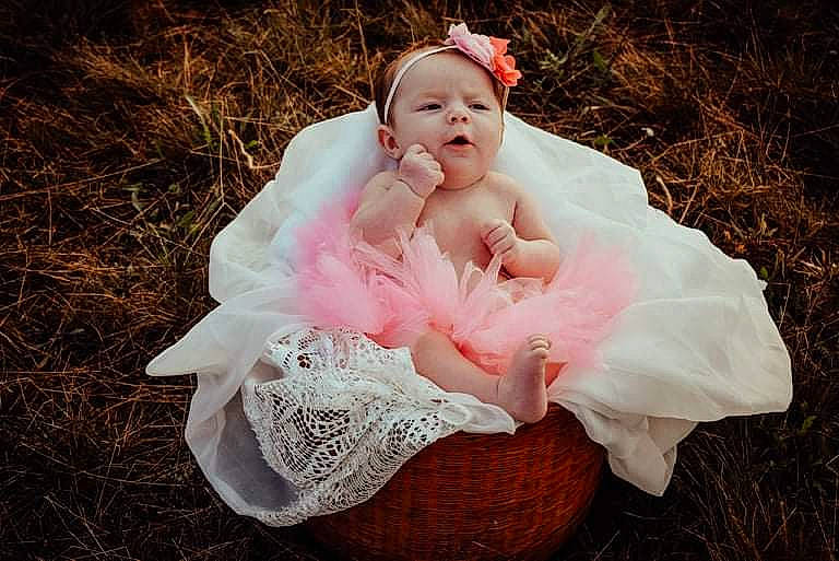 Lydia is registered to the contest to win money with this photo: baby, baby_toddler_clothing, bridal_accessory, bridal_clothing, dress, eye, face, flash_photography, grass, hair_accessory, happy, head, headgear, headpiece, human_body, people_in_nature, person, petal, plant, sitting