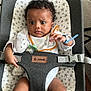 baby, infant, baby_seat, teddy_bear, bib, curly_hair, pacifier, star_pattern, wooden_floor, carpet, child, indoor, clothing, cute, expression, person, seatbelt, toy, sitting, young_child