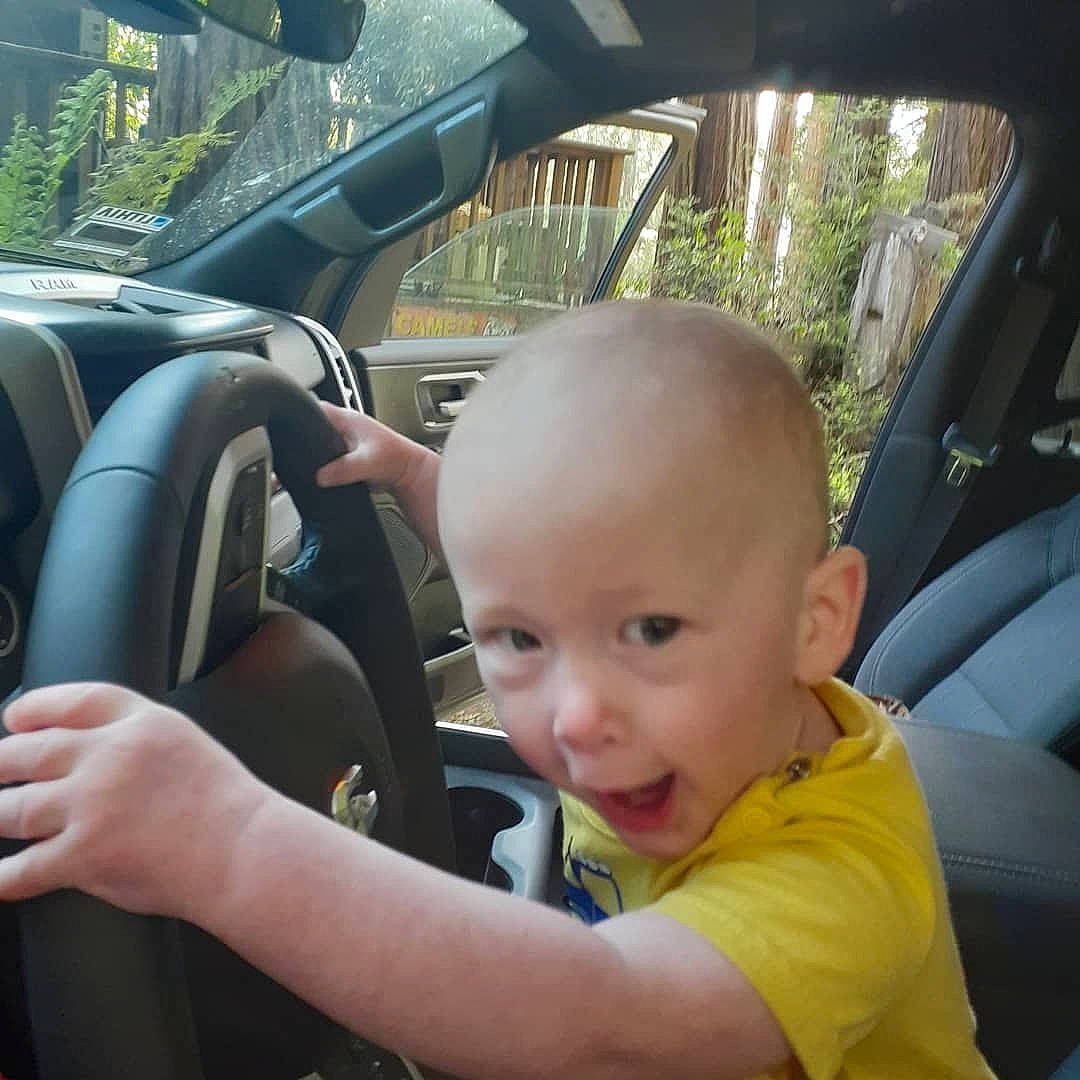 Arthur Gage Pittman is registered to the contest to win money with this photo: auto_part, automotive_design, automotive_exterior, automotive_mirror, car, car_seat, car_seat_cover, mode_of_transport, motor_vehicle, person, personal_luxury_car, plant, rear_view_mirror, smile, steering_part, steering_wheel, toddler, tree, vehicle, vehicle_door