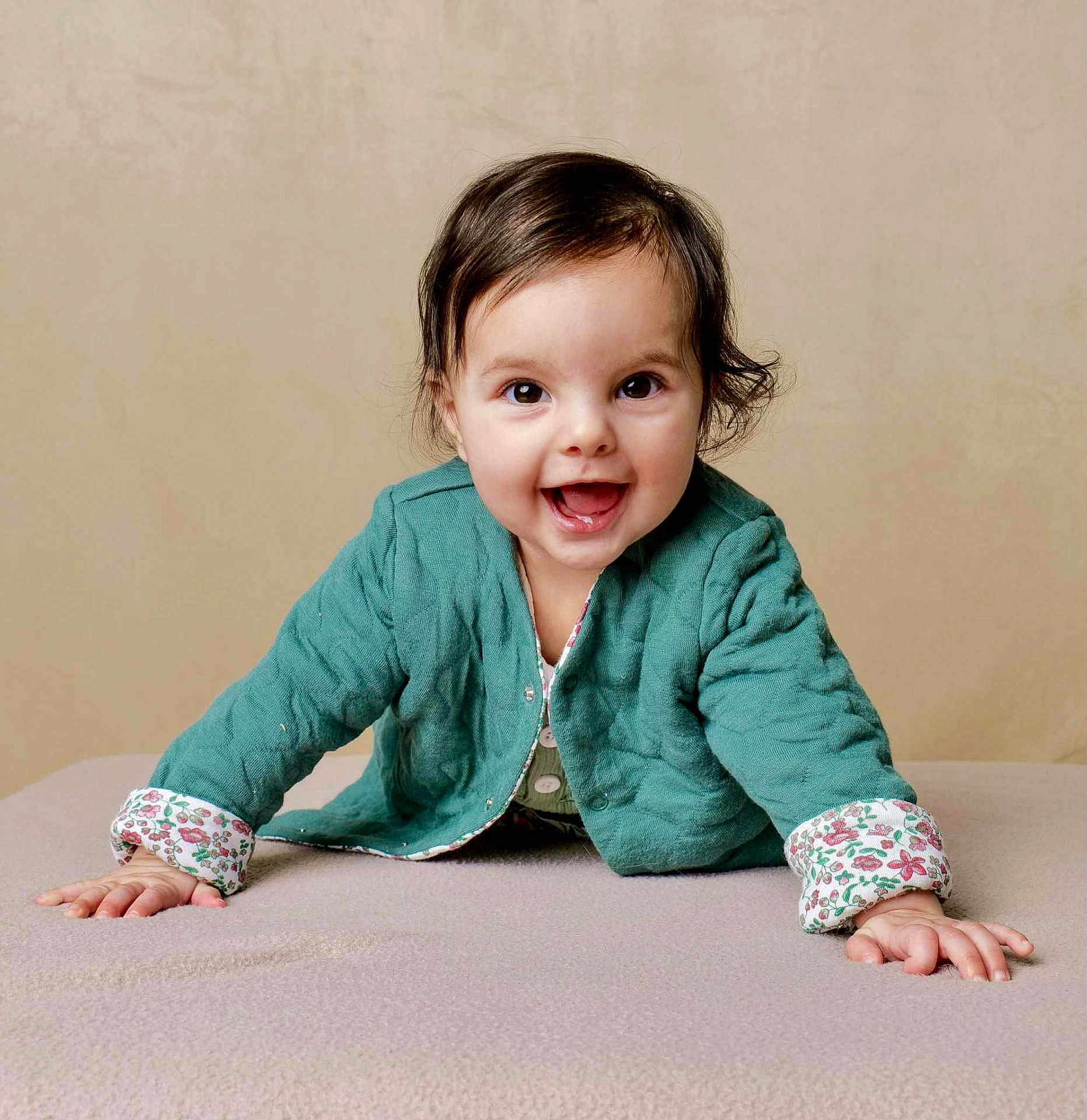 Romy participe au concours pour gagner de l'argent avec cette photo : baby, child, smile, crawling, green_jacket, floral_cuffs, happy, indoors, portrait, cute, young_child, face, hands, cozy, warm_clothing, expression, joyful, looking_at_camera, soft_background, infant