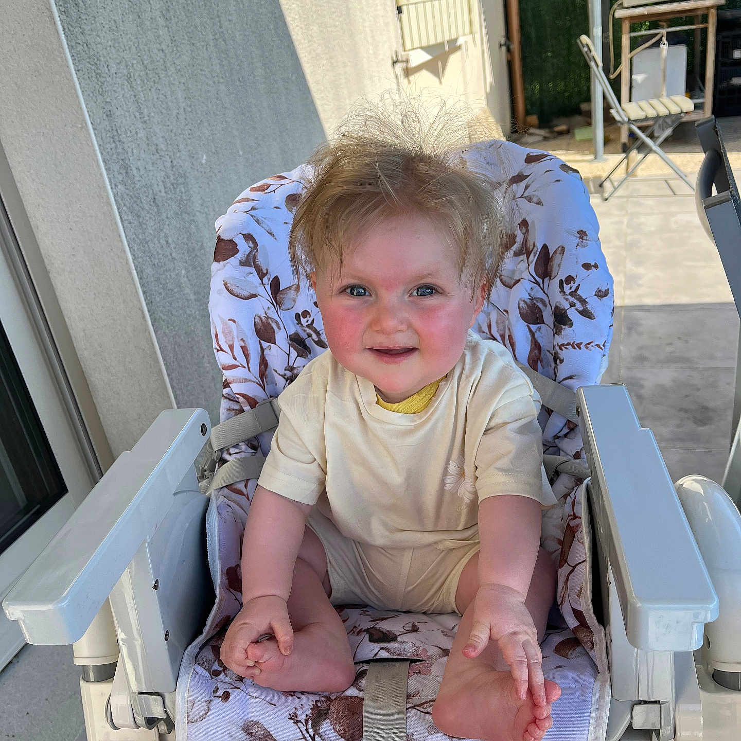 Ambre participe au concours pour gagner de l'argent avec cette photo : baby, child, clothing, door, fabric, face, foot, furniture, hair, hand, happy, high_chair, outdoor, patio, seat, skin, smiling, sunlight, toddler, window
