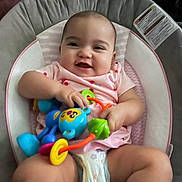 Malia joined the competition — help win amazing prizes! baby, infant, smile, toy, colorful_toy, baby_seat, diaper, pink_clothing, happy, child, cute, indoor, person, play, sitting, cushion, face, hands, legs, home