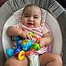 baby, infant, smile, toy, colorful_toy, baby_seat, diaper, pink_clothing, happy, child, cute, indoor, person, play, sitting, cushion, face, hands, legs, home