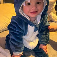 Maël participe au concours pour gagner de l'argent avec cette photo : baby, blanket, child, costume, cozy, cute, expression, face, hand, hood, indoors, playful, plush, shark_onesie, sitting, smiling, socks, teeth, toddler, warm_clothing
