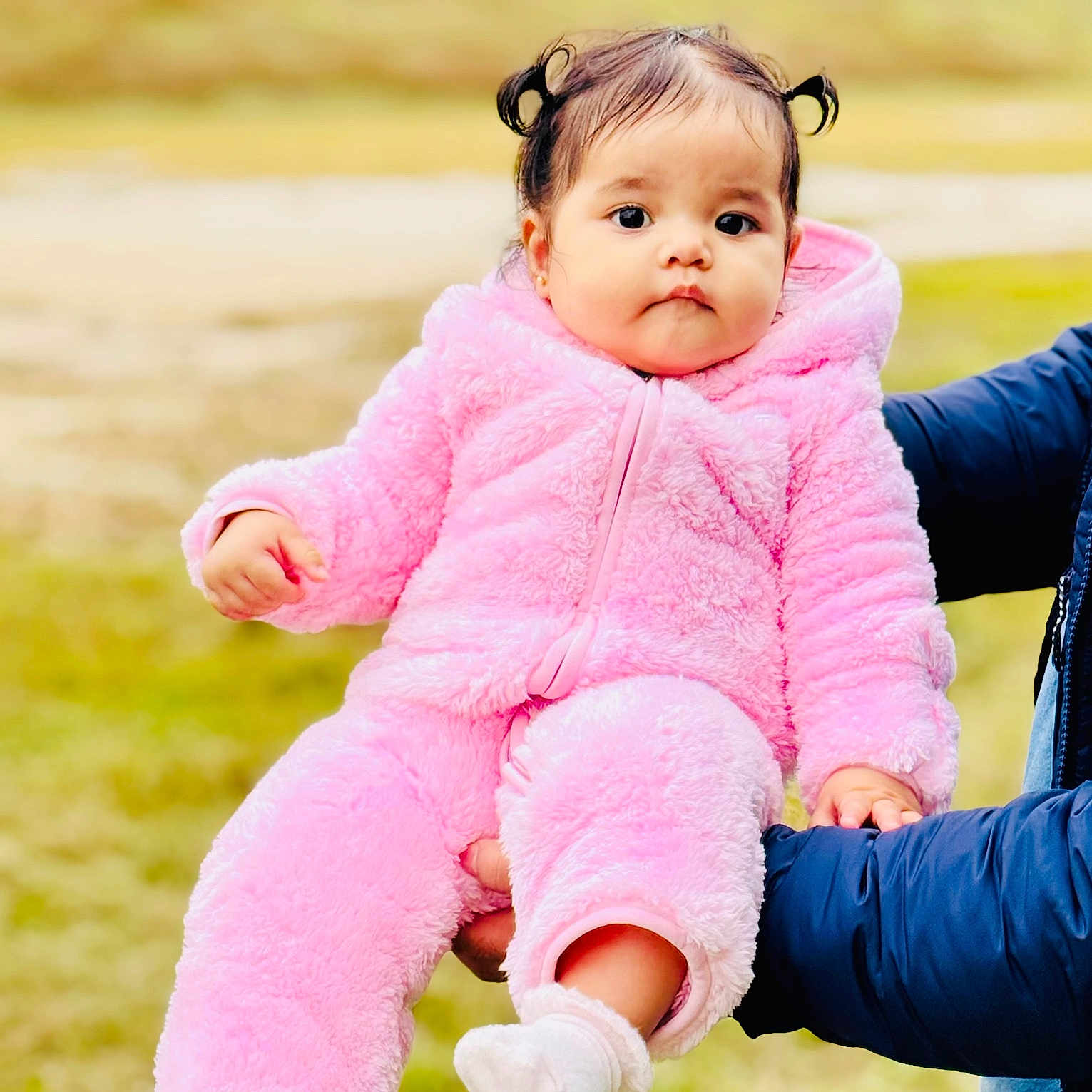 Elissa joined the competition — help win amazing prizes! baby, child, cute, expressionless, face, fluffy, grass, hands, holding, onesie, outdoor, person, person_holding, pink_clothing, portrait, small_child, sock, warm_clothing, winter_wear, young_child