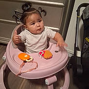 Amun-Ra is registered to the contest to win money with this photo: baby, baby_walker, child, floor, furniture, hair_bows, happy, home, indoor, infant, pigtails, pink_walker, playroom, portrait, rattle, sitting, smiling, thumbs_up, toy, white_shirt