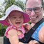 adult, baby, baby_carrier, blue, child, closeup, cloudy_sky, glasses, greenery, happy, hat, laughing, nature, outdoor, person, pink, smiling, summer_clothing, sunhat, trees