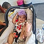 Tikena a rejoint le concours — aidez-le/la à gagner de superbes lots ! baby, baby_carrier, child, clothing, curious, floor, flower, foot, happy, headband, indoor, infant, person, playful, seat, smile, stool, table, toddler, water_bottle