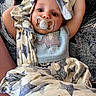 Caden is registered to the contest to win money with this photo: baby, infant, child, portrait, face, eyes, pacifier, smiling, lying_down, blanket, stars, patterned_fabric, blue_clothing, onesie, elephant_design, indoor, cozy, close_up, sitting_area, happy