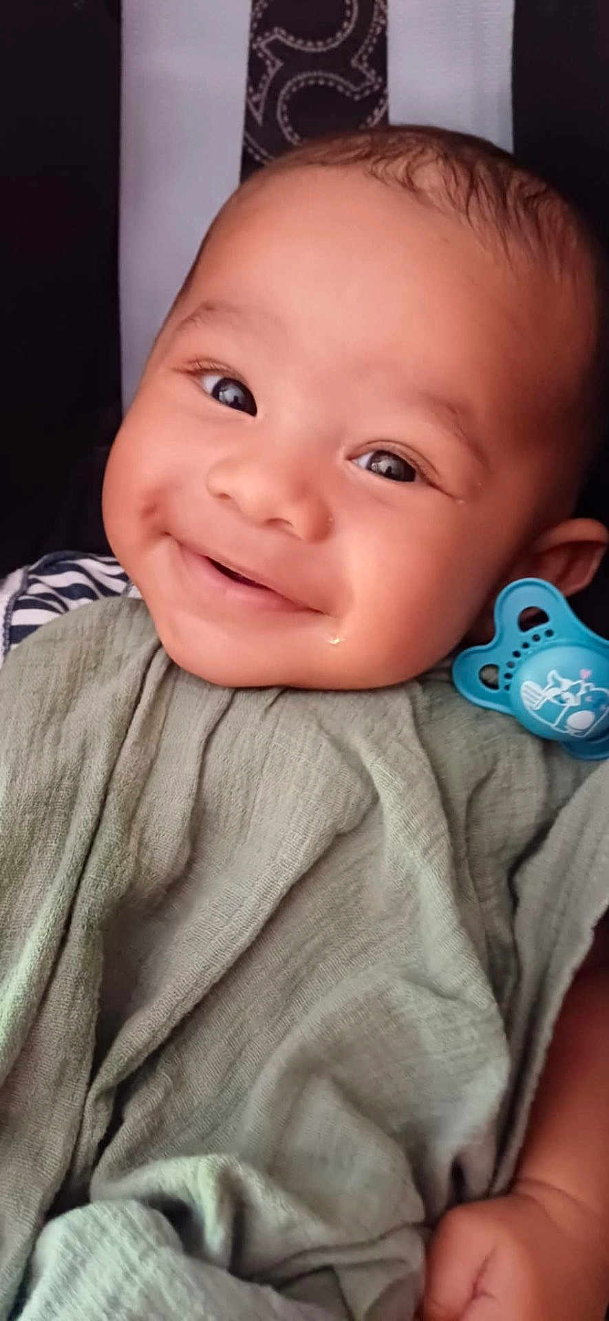 Uriel participe au concours pour gagner de l'argent avec cette photo : baby, smiling, face, blanket, pacifier, infant, child, cute, happy, portrait, closeup, skin, clothing, hand, expression, indoors, person, head, cheeks, eyes