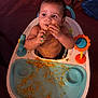 Zamarii is registered to the contest to win money with this photo: baby, carpet, child, cute, eating, face, food, hands, happy, high_chair, indoor, infant, meal, messy, mouth, orange_food, playful, seat, table, toy